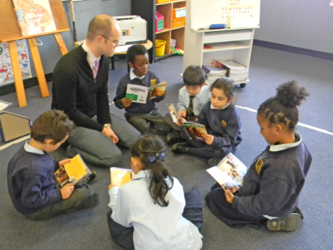 Ben Munday with students reading at Holy Family Primary