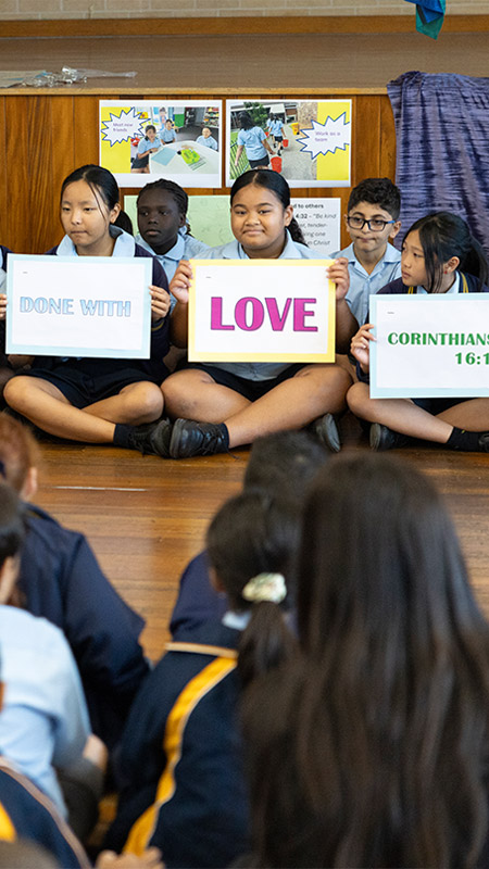 Students holding signs which form Corinthians 16 14 qoute