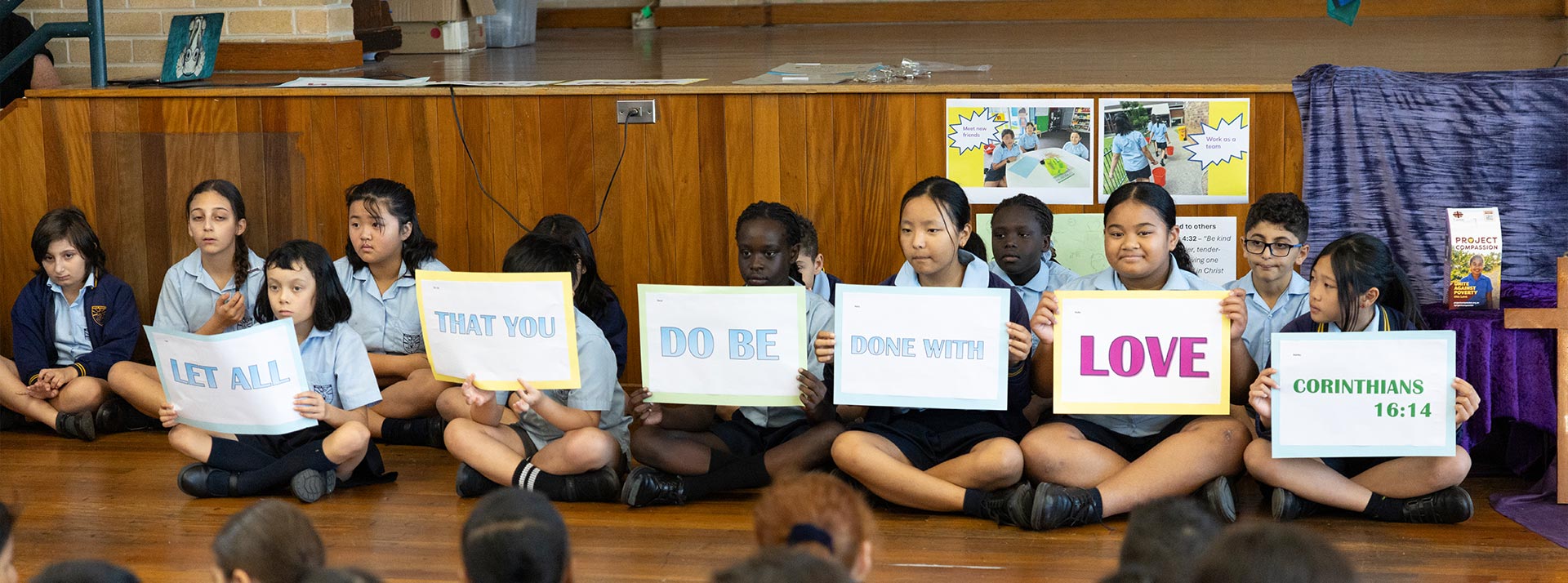 Students holding signs which form Corinthians 16 14 qoute