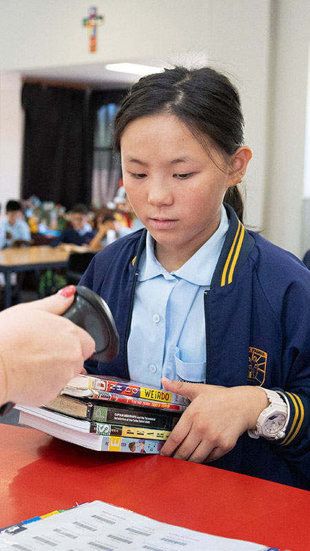 Student borrowing books at Holy Family East Granville primary school library