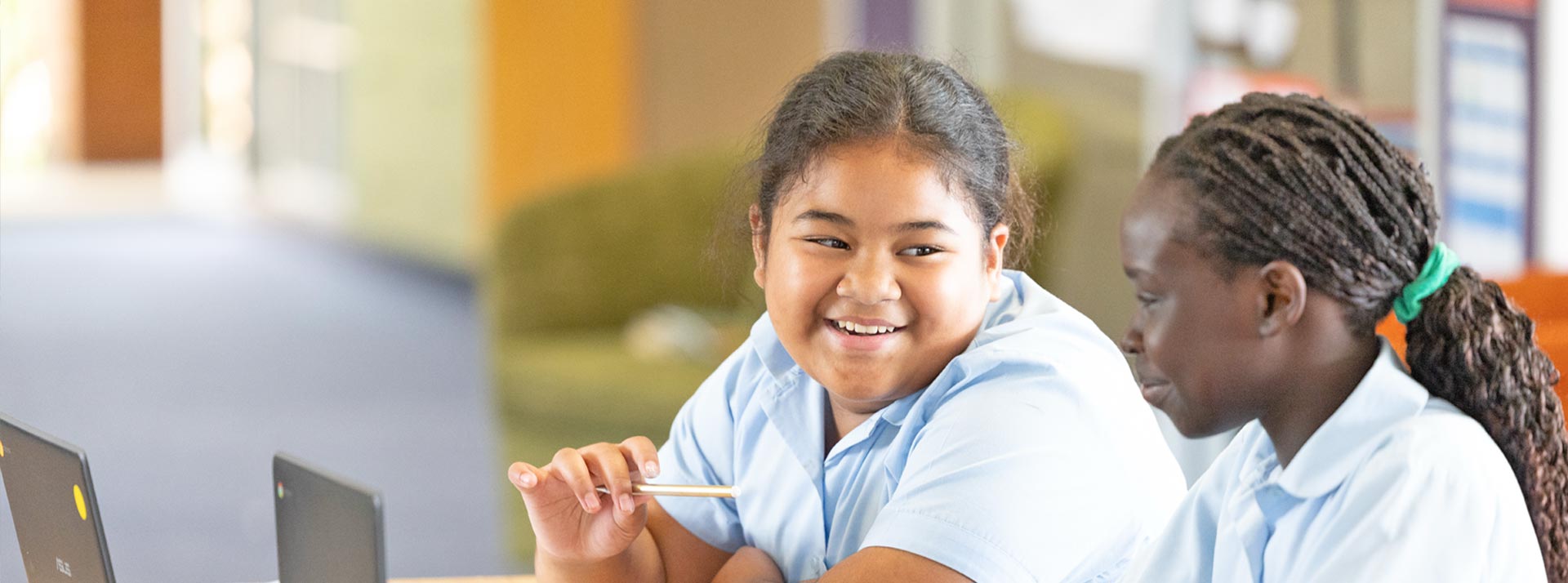 Two students smiling and working from Chromebooks at Holy Family Primary East Granville