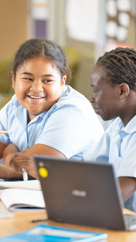 Two students smiling and working from Chromebooks at Holy Family Primary East Granville