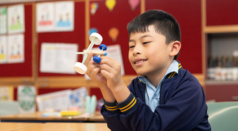 Holy Family Primary, East Granville student crafting something from bottle caps, straws and pegs