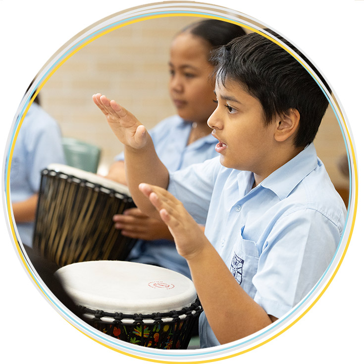 Holy Family Primary East Ganville student playing a drum