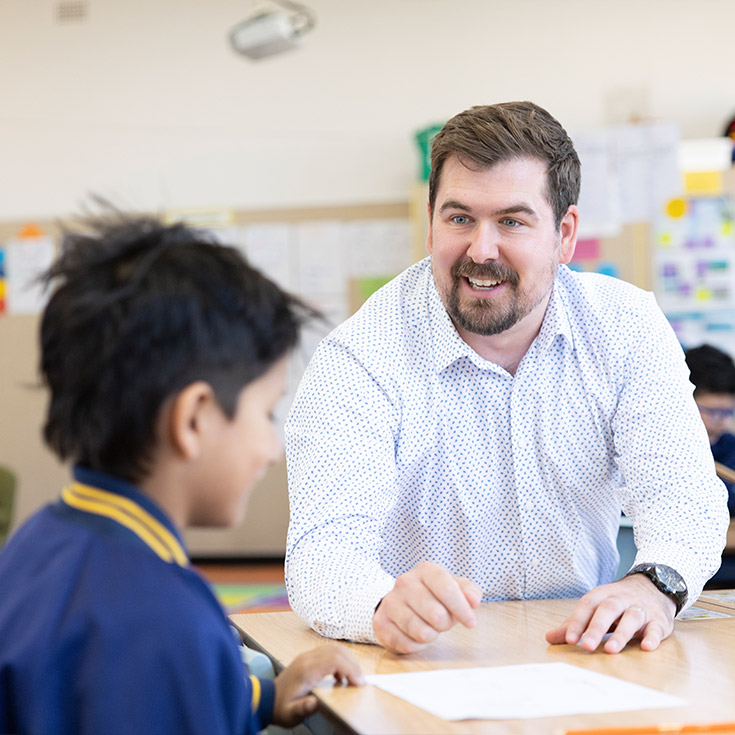 Male teacher at Holy Family Primary, East Granville engaging with student learning