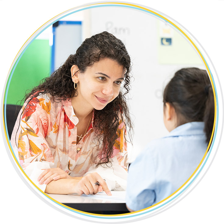 Teacher assisting student with their reading at Holy Family Primary, East Granville